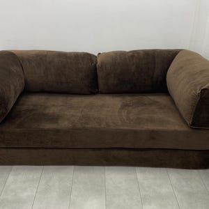 May include: A white ceramic mug with a black handle and the text "But First, Coffee" in a black, handwritten-style font. The mug is on a white surface.