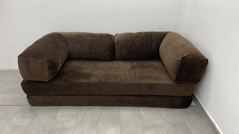 May include: A white ceramic mug with a black handle and the text "But First, Coffee" in a black, handwritten-style font. The mug is on a white surface.