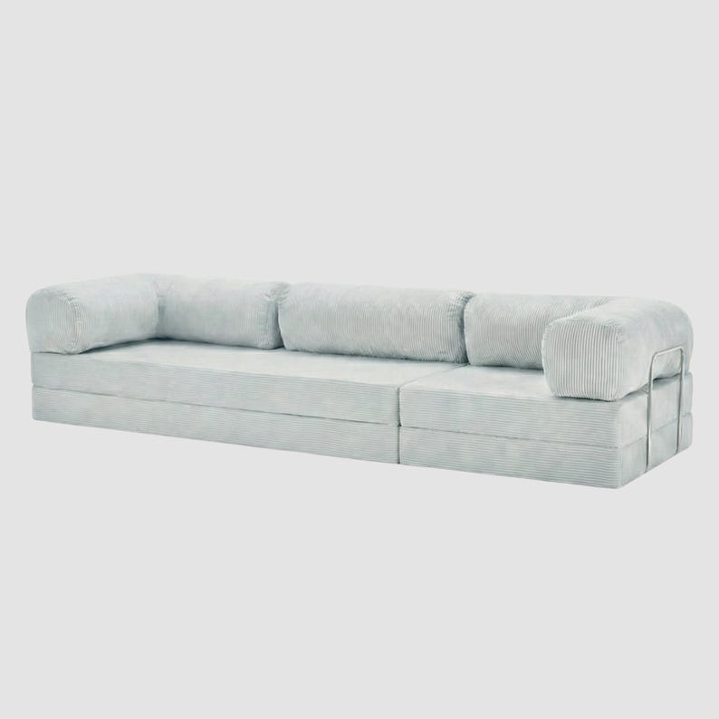 May include: A light blue modular sofa with a corduroy texture. The sofa has a low profile with a rectangular shape and rounded armrests. A silver metal frame supports the armrest. The sofa is designed for comfort and modern living.
