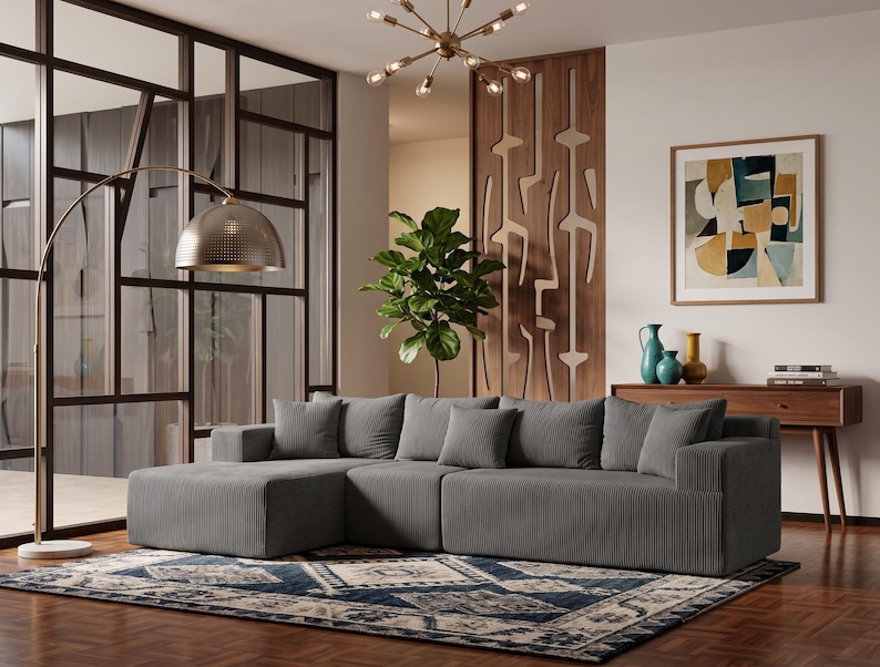 May include: A modern living room featuring a gray sectional sofa with matching throw pillows. A patterned rug in blue and cream tones sits on a hardwood floor. A gold arched floor lamp and abstract art complete the space.