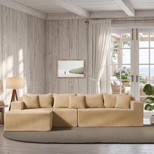 May include: A light beige corduroy sectional sofa with matching throw pillows. The sofa is in a bright, airy living room with white curtains, a wooden side table, and a potted plant. A framed picture hangs on the wall.