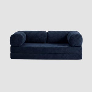 May include: A navy blue corduroy sofa with rounded armrests and a low profile. The sofa is composed of several stacked sections, creating a modular design. The fabric has a ribbed texture.