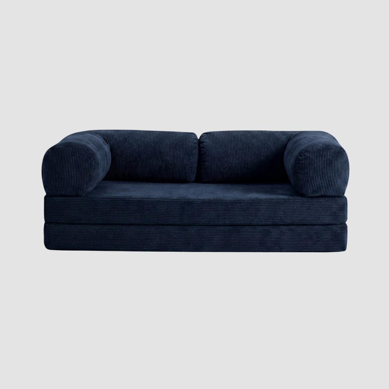 May include: A navy blue corduroy sofa with rounded armrests and a low profile. The sofa is composed of several stacked sections, creating a modular design. The fabric has a ribbed texture.