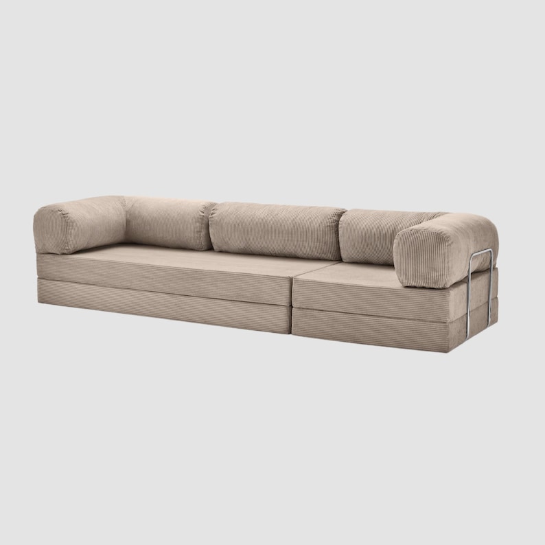 May include: A modular beige corduroy sofa with rounded armrests and back cushions. The sofa is composed of several sections, offering a customizable seating arrangement. The design features a minimalist aesthetic with a neutral color palette.