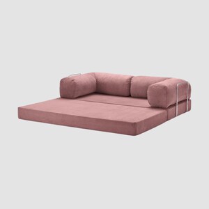 Puede incluir: Un sof&aacute; modular rosa empolvado con textura de pana. El sof&aacute; tiene un perfil bajo con una base rectangular y dos reposabrazos. Los reposabrazos tienen un marco de metal plateado. El sof&aacute; est&aacute; dise&ntilde;ado para ser vers&aacute;til.