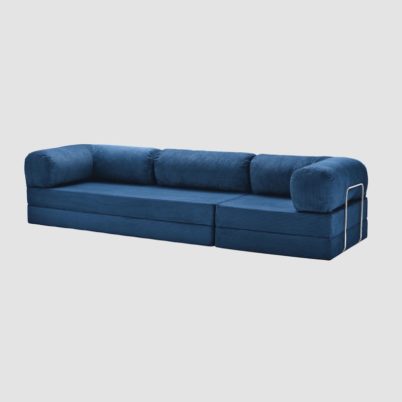 May include: A modular blue corduroy sofa with rounded armrests and backrests. The sofa has a low profile and a modern design, with a metal frame on the armrest. The sofa is made of a soft, textured fabric.
