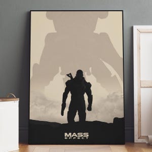 May include: A framed poster featuring a silhouette of a figure with a weapon, set against a backdrop of a larger, indistinct form. The words "MASS EFFECT" are at the bottom in a bold font. The color palette is primarily black and beige.
