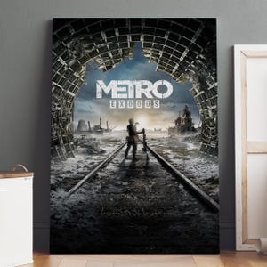 May include: A framed poster for the video game "Metro Exodus." The artwork depicts a post-apocalyptic scene with a figure standing on train tracks, holding a rifle. The title is prominently displayed in white letters against a backdrop of a destroyed cityscape.