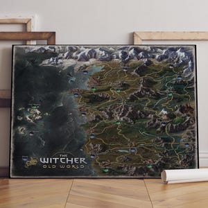 May include: A framed map of the Witcher Old World, featuring a detailed fantasy landscape with mountains, forests, and bodies of water. The map is predominantly green, brown, and blue, with the title text at the bottom.