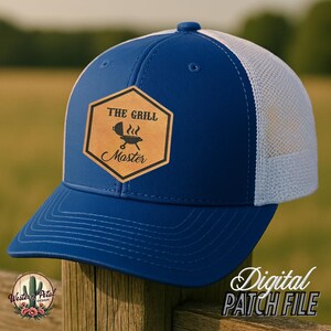 Könnte beinhalten: Blau-weiße Trucker-Kappe mit einem braunen Leder-Patch, auf dem "The Grill Master" mit einem Grill- und Flammen-Motiv steht.