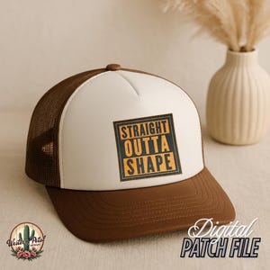 May include: A brown and white trucker hat with a brown mesh back. The front of the hat has a white patch with the text "STRAIGHT OUTTA SHAPE" in orange and black.
