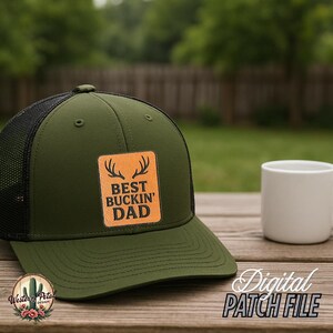 May include: A green and black trucker hat with a brown leather patch that says "Best Buckin' Dad" with antlers above the text. The patch is on a green background.