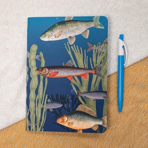 May include: A blue notebook with a colorful illustration of fish swimming among seaweed. The fish are a variety of colors, including red, orange, and yellow. The notebook is a great way to keep track of your thoughts and ideas.