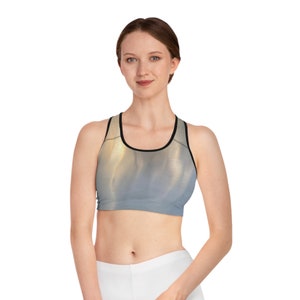 May include: A grey and gold sports bra with black trim. The bra has a racerback style and a scoop neck.