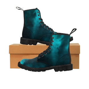May include: A pair of black lace-up boots with a teal and blue tie-dye pattern. The boots are sitting on a brown cardboard box.