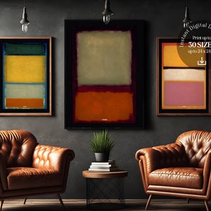 May include: Three abstract paintings in a minimalist style with geometric shapes and bold colors. The paintings are framed in wood and hung on a dark gray wall. The paintings are in a living room setting with two leather armchairs and a small table.