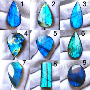 May include: Nine polished labradorite gemstones in various shapes, including teardrop and oval. The stones display iridescent blue, green, and gold flashes. Each stone is unique, showcasing natural patterns and colors.