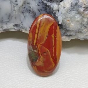 Puede incluir: Una piedra preciosa ovalada en cabuj&oacute;n con un patr&oacute;n de remolino en tonos rojos, amarillos y verdes.