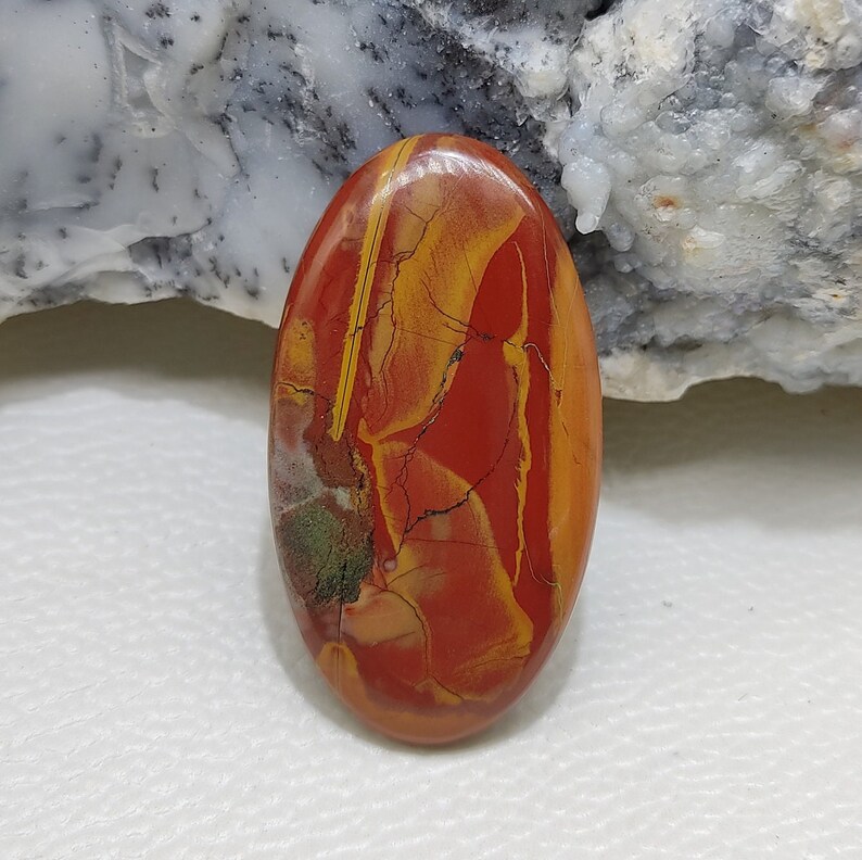 Puede incluir: Una piedra preciosa ovalada en cabuj&oacute;n con un patr&oacute;n de remolino en tonos rojos, amarillos y verdes.