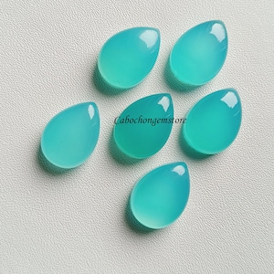 May include: Six teardrop-shaped cabochons in a light turquoise color. The stones are smooth and polished, and they are arranged in a cluster on a white surface.