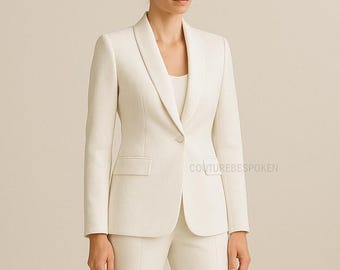 May include: Ivory-colored suit featuring a tailored blazer with a shawl collar and a single-button closure. The blazer has a front pocket on each side. The suit is paired with matching trousers. The text "COUTUREBESPOKEN" is visible on the right side.