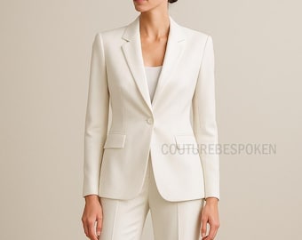 May include: Ivory-colored suit featuring a tailored blazer with a single-button closure and a notched lapel. The suit includes matching trousers. The text "COUTUREBESPOKEN" is visible on the right side of the image. The suit is a classic style.
