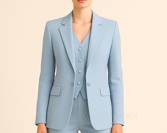Puede incluir: Un traje de tres piezas azul claro, que incluye una americana, un chaleco y un pantalón. La americana tiene dos bolsillos delanteros y solapas con muescas. El chaleco tiene cierre de botones. El traje es de tela lisa.