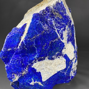 Op de afbeelding: Een grote, ruwe, blauwe lapis lazuli steen met witte calciet aderen en vlekken van pyriet.