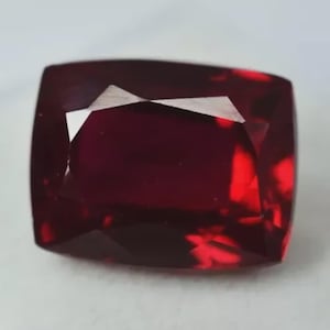 Può includere: Una pietra preziosa di colore rosso intenso con taglio rettangolare e finitura lucida. La pietra preziosa è sfaccettata e ha un alto grado di brillantezza.