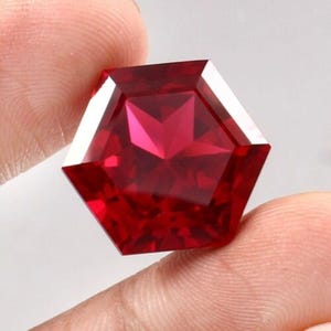 May include: A deep red hexagonal gemstone with a star-shaped pattern inside.