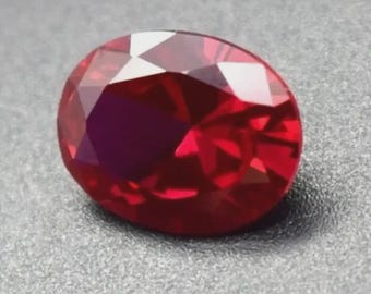 May include: A deep red oval-shaped gemstone with facets.