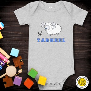 Short sleeve one piece Lil Tarheel text on grey onesie with fluffy ram with blue heart nose  | Team Mascot | Newborn | School Spirit. On wood background with bright scattered toys.