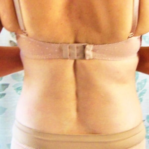 May include: A nude-colored bra and matching underwear with a polka dot pattern. The bra has adjustable straps and a hook and eye closure in the back. The underwear has a lace trim.