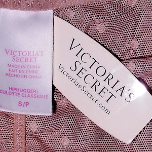 May include: A pink mesh fabric with a white tag that says "Victoria's Secret" and "Hiphugger/Culotte Classique S/P". The tag also says "Made in China, Fait en Chine, Hecho en China".