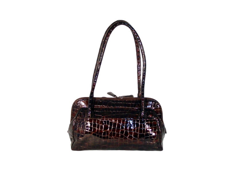 Pu&ograve; includere: Una borsa a mano in pelle marrone con stampa coccodrillo e due manici superiori.