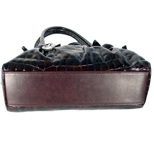 Pu&ograve; includere: Una borsa a mano in pelle marrone con stampa coccodrilo e chiusura argentata. La borsa &egrave; foderata in pelle marrone.