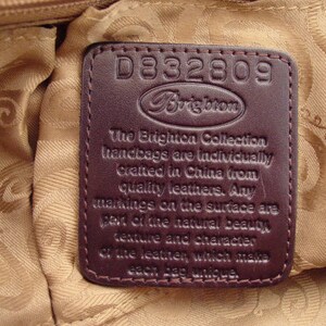 Pu&ograve; includere: Un'etichetta per borsa a mano in pelle marrone con il testo "D332809 Brighton The Brighton Collection handbags are individually created in China from quality leathers. Any markings on the surface are part of the natural beauty, texture and character of the leather which makes each bag unique."