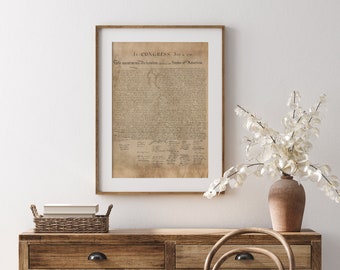 May include: A framed print of the Declaration of Independence, with the text "In CONGRESS, July 4, 1776. The unanimous Declaration of the thirteen united States of America." The print is hanging on a white wall above a wooden dresser with a wicker basket on top.
