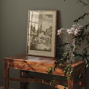 May include: A framed black and white print of a historical scene depicting the Boston Massacre on March 5, 1770. The print shows a group of people gathered in a street with a church in the background. The print is framed in a simple wooden frame.