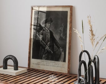 May include: A framed black and white portrait of John Paul Jones, Commander in Chief of the United States Navy, with the text "JOHN PAUL JONES, Commander in Chief of the Navy of the THIRTEEN UNITED STATES OF NORTH AMERICA, 1776."