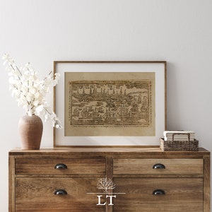 Puede incluir: Un mapa vintage enmarcado de una ciudad con barcos y edificios. El mapa está en blanco y negro y tiene un fondo marrón. El marco es de madera marrón.