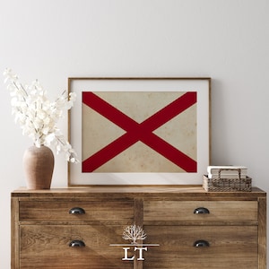 Puede incluir: Una impresi&oacute;n enmarcada de una cruz roja sobre un fondo blanco. La impresi&oacute;n est&aacute; colgada en una pared blanca sobre una c&oacute;moda de madera con dos cajones.
