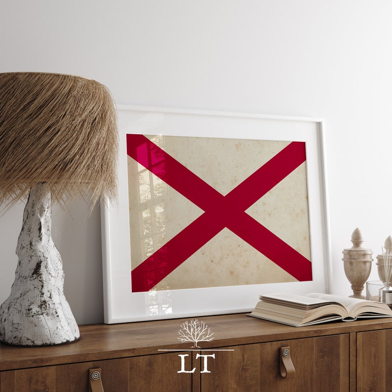 Puede incluir: Una impresi&oacute;n enmarcada de una cruz roja sobre un fondo blanco. La impresi&oacute;n est&aacute; colgada en una pared blanca sobre una c&oacute;moda de madera con una l&aacute;mpara y libros.