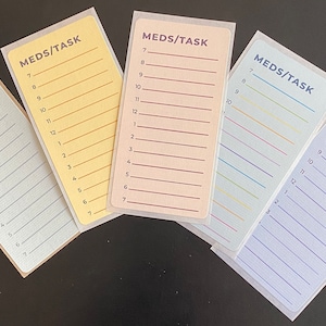May include: Five different colored reminder cards with the text "MEDS/TASK" at the top and numbered lines from 7 to 7. The cards are yellow, pink, blue, light blue, and brown.