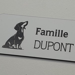 Könnte beinhalten: Weißer rechteckiger Namensschild mit einer schwarzen Silhouette eines Dackels, der nach oben schaut. Der Text "Famille DUPONT & DUPONT" ist in Schwarz gedruckt.