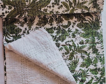 May include: A white and green kantha quilt with a floral pattern. The quilt is folded in half and the inside is visible. The quilt is made of cotton and is hand-stitched.
