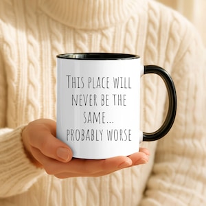 May include: A white ceramic mug with a black handle and rim, featuring the black printed text: This place will never be the same... probably worse. The mug has a cylindrical shape and a smooth finish, designed for holding hot or cold beverages.