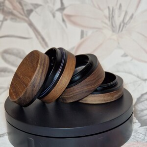 Puede incluir: Cuatro piezas de molinillo de madera con detalles en negro y azul. Las piezas del molinillo están apiladas una encima de la otra sobre una superficie negra.