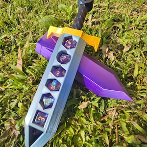 May include: A silver sword with a purple and yellow handle. The sword has a slot for dice and is holding several purple and gold dice.