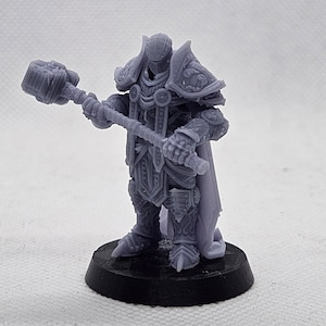 Könnte beinhalten: Eine graue, 3D-gedruckte Miniatur eines Krieger-Figuren in Rüstung, der einen Hammer hält. Die Figur steht auf einem schwarzen Sockel.